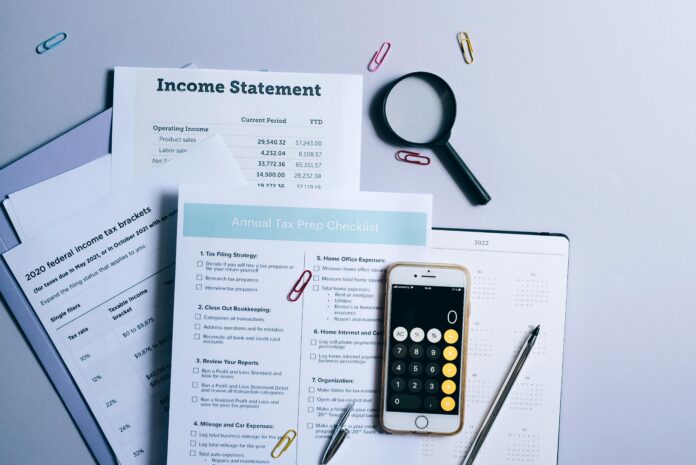 An organized desk with tax documents, checklist, and gadgets for tax preparation.